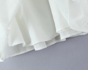 Close-up of white floral embroidery with hollow lace pattern and inner lining detail