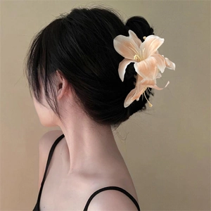 Detail view of a large lily flower hair claw clip in cream and orange gradient on hair