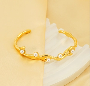 Macro detail of 18K gold-plated irregular wave bangle with inlaid elegant pearls