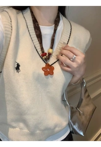 Detail of ethnic style fabric necklace featuring an orange resin flower pendant and beads