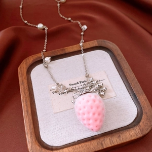 Detailed view of pink flocked strawberry pendant with pearls on a silver necklace