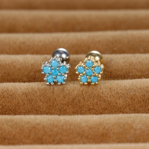 Macro detail of gold and silver flower stud earrings with blue zircon inlays