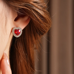 Primo piano di una modella con orecchini a cuore vintage in gemma rossa e diamanti