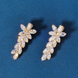 Detailed close-up of golden floral leaf earrings with sparkling cubic zirconia crystals