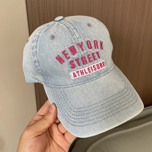 Close-up of pink and white New York embroidery on washed blue denim baseball cap