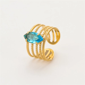 Macro shot of gold-plated multi-layer ring featuring a marquise-cut blue gemstone