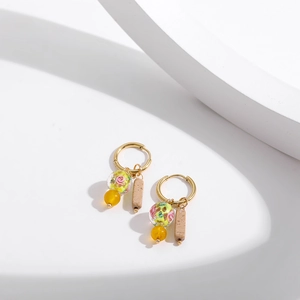 Detailed view of Chinese style gold hoops with floral glass, yellow beads, and stone charms