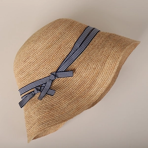 Straw sun hat with blue striped ribbon and bow on light gray background