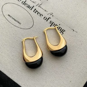 Detail of irregular gold metal earrings with chocolate resin droplets on canvas