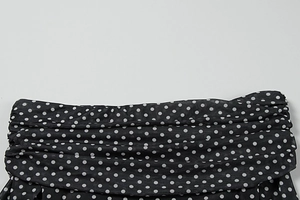 Detail shot of the pleated waist on a black polka dot mesh dress with layered mesh fabric