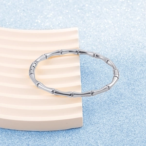 Polished stainless steel bamboo-style bangle with a minimalist design on a sleek display