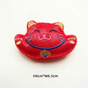 Macro view of a red lucky cat fabric patch with embroidery detailing, 4cm by 6.5cm