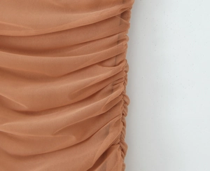 Détail de couture froncée sur une robe en tulle caramel montrant les plis du tissu