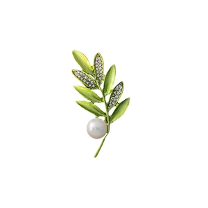Macro detail of green leaf brooch featuring sparkling crystals and a white pearl