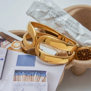 Macro view of gold-plated stainless steel open cuff with irregular hollow-out design