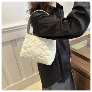 Détail d'un sac à bandoulière blanc matelassé avec motifs de cœurs sur modèle
