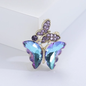 Close-up of dual butterfly brooch with blue-purple crystal wings and gold-tone finish