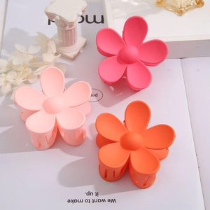 Detail of candy-colored matte flower hair claws in pink and orange on a white surface