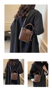 Detail view of a brown leather bucket bag with top handle and woven tassel ornament