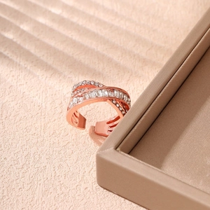 Close-up of rose gold criss-cross ring with sparkling zircon stones on soft background