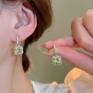 Macro detail of square yellow zircon earrings featuring a pave set silver base