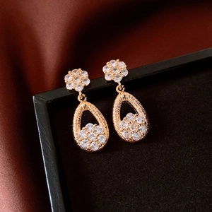 Macro detail of 18K gold-plated teardrop earrings with floral zircon accents