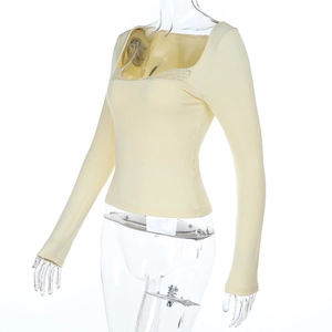 Détail de la dentelle élégante sur le décolleté de ce haut ajusté jaune clair à manches longues