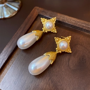 Vue détaillée de boucles d'oreilles vintage avec étoile et perle sur plateau en bois