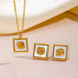 Gold rose necklace and earrings set with white shell inlay on a soft beige background