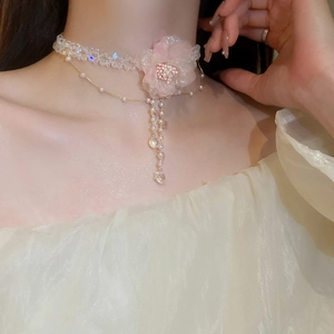Detail eines rosa Stoffblumen-Chokers mit Perlen und Perlenquasten an einem Modellhals