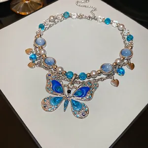 Collier multi-rangs élégant avec pendentif papillon bleu et perles sur carte blanche