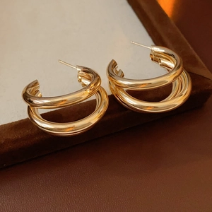 Gros plan de boucles d'oreilles dorées multicouches en forme de C sur velours
