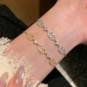 Detailed close-up of 18k gold plated crossed circles bracelet with sparkling zircons