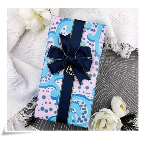 Close-up of pastel blue and pink pattern gift wrap with elegant dark blue ribbon bow