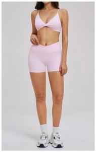 Detail of pink yoga set showing twist-front sports bra and crossover waist biker shorts
