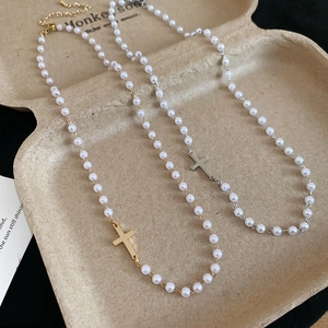 Close-up of gold and silver cross pendants on pearl necklaces in a luxury tray