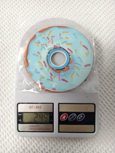 Nahaufnahme eines Donut-Party-Aufklebers auf einer Waage mit Gewichtsanzeige von 24,5 g