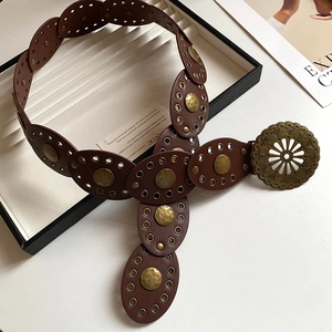 Detailed shot of dark brown bohemian belt with metal studs and engraved hollow buckle