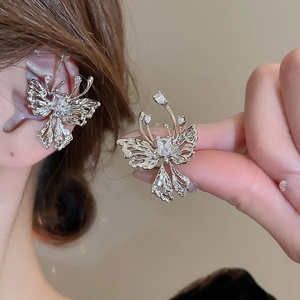 Detailed view of silver bow-shaped ear cuff with hollow wings and sparkling zircons