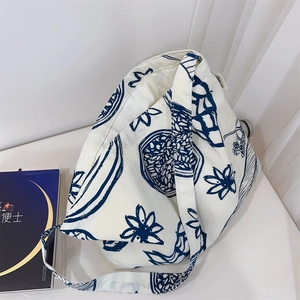 Détail du sac cabas en toile à fleurs bleues avec bandoulière large et étiquette tissée