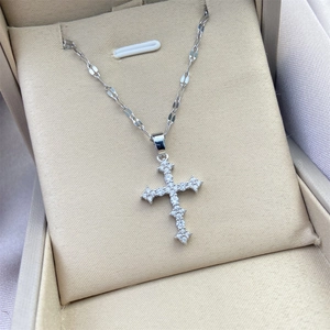 Macro detail of silver plated cross pendant with pavé zircon stones in a jewelry box