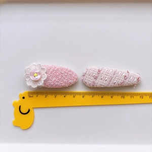 Pink tweed bow hair clips with lace flower and button details shown with scale