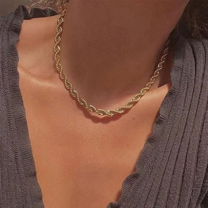 Detailed view of a gold braided rope chain necklace worn on a female neck in retro style