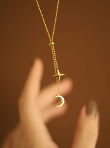 Detail of gold star and moon pendant necklace with adjustable bead chain design