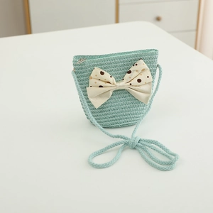 Detail of mint green straw shoulder bag with a cream polka dot bow for kids