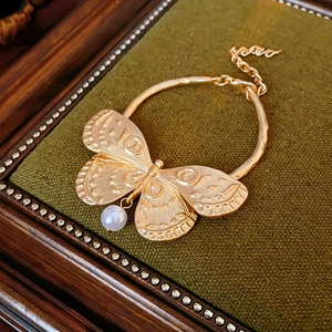 Detailed macro view of vintage butterfly bracelet with gold texture and pearl drop