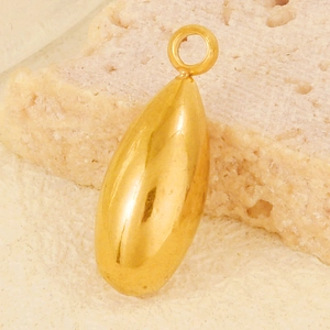 Macro detail of polished gold teardrop pendant on a natural stone background