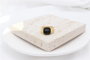 Macro detail of minimalist gold ring with square black inlay on natural stone block