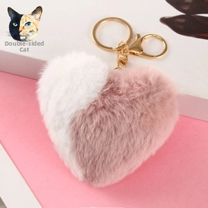 Detail of plush heart-shaped keychain with pink and white faux fur and golden lobster clasp