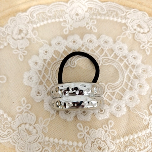 Close-up of a silver hammered metal cuff hair tie on elegant lace background